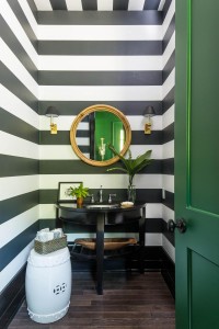 Designed by Bill Ingram, the bold striped wallpaper create drama in the powder room.            