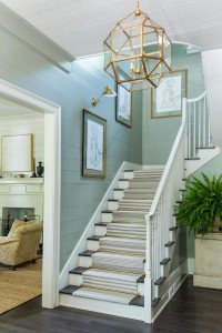 An elegant staircase extends the foyer, and shiplap and gold finishes accent the design.          