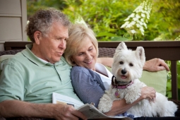 Residents spend a morning relaxing with their Westie on the front porch of a custom home.  