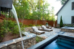 This backyard oasis includes a dipping pool, hot tub, and two comfortable chaise lounge chairs.      