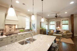 Marble countertops and pendant light fixtures beautifully accent this kitchen/living room space.                               
