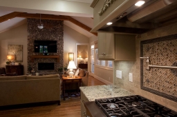 Marble countertops, a unique backsplash, and a stonework fireplace beautifully accent this open-concept living space.                               