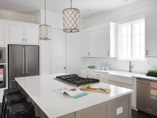 Quartz counters, antique gold finishes, shiplap walls, and a farmhouse kitchen sink complete a contemporary clean design in this kitchen.  Photo: Tommy Daspit         